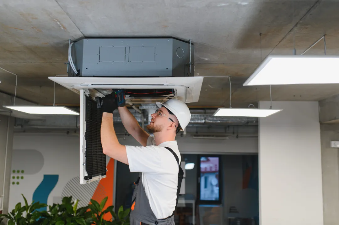Professional hvac engineer installing and maintaining a ventilation unit on the office ceiling, ensuring proper climate control